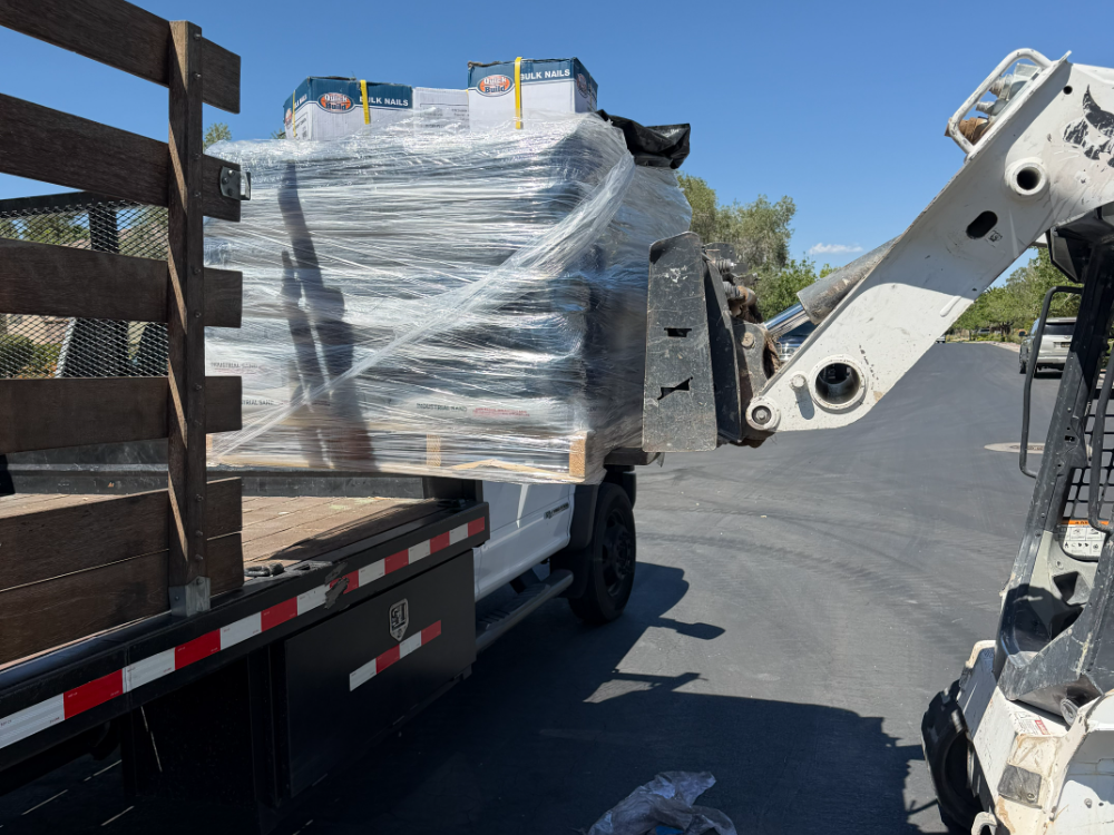 A pallet of infill and nails being unloaded at a job site